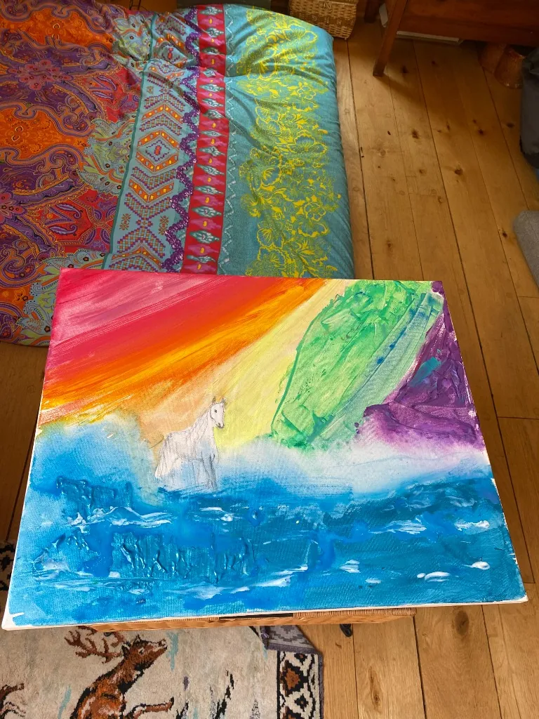 A vibrant rainbow colored canvas with a white horse in the center
