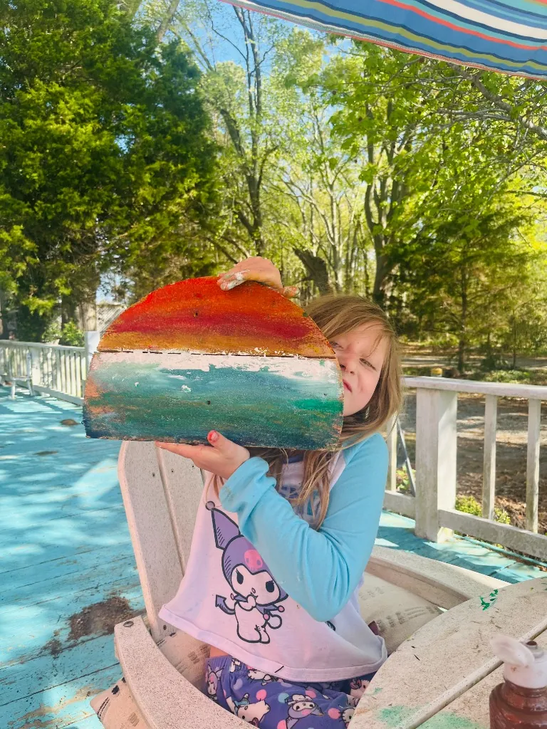 A proud young artist holding her wooden board painting